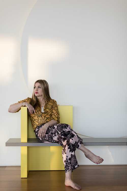 top NYC interior designer sitting on yellow chair in patterned clothing